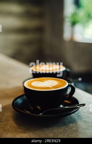 Une image rapprochée d'une tasse de café fraîchement préparé avec un latte complexe versé sur le dessus Banque D'Images