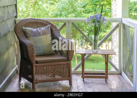 Fauteuil en rotin et table avec un vase de fleurs sur une véranda en bois, Tanzanie, Afrique de l'est, gros plan Banque D'Images