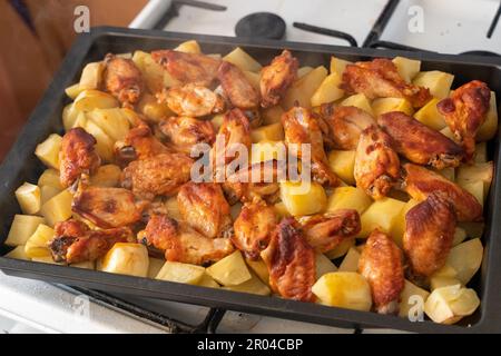 Pommes de terre vapeur fraîchement rôties avec ailes de poulet dans un moule à pâtisserie en métal Banque D'Images