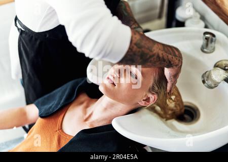 Obtenir vos cheveux lavés est aussi si thérapeutique. une jeune femme attirante se laver les cheveux et stylisée par un coiffeur à l'intérieur d'un salon de coiffure. Banque D'Images