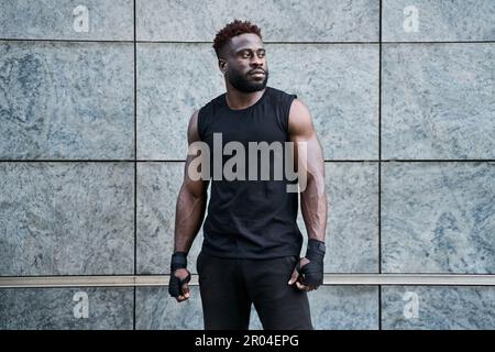 Solide confiant sportif jeune homme noir boxeur combattant debout à l'extérieur. Banque D'Images