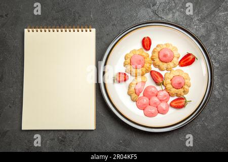 vue de dessus délicieux petits biscuits avec crème rose à l'intérieur de l'assiette sur fond gris biscuits biscuit sucre thé gâteau sucré Banque D'Images