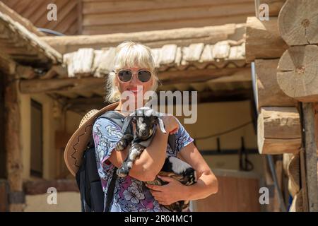 cowgirl interagit avec le billy, le caressant et le petting, créant un lien entre eux. Rencontre entre la femme et l'animal de ferme est un Banque D'Images