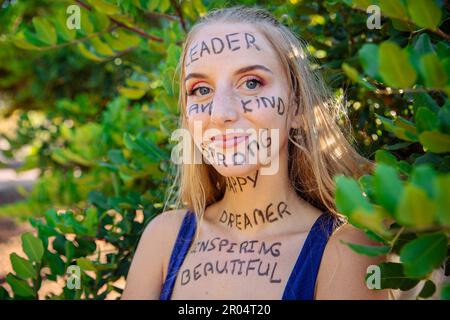 Portrait d'une jeune femme avec des mots de motivation écrits sur sa peau, confiante femme habilitée. Banque D'Images