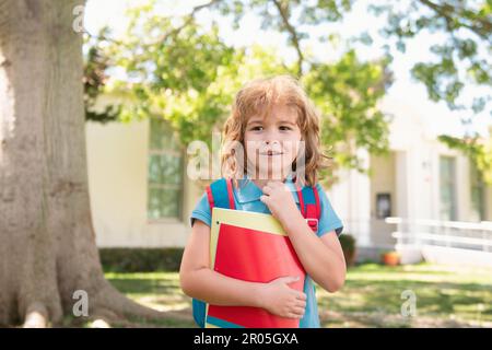 Enfant avec sacs à dos debout dans le parc près de l'école. Élèves avec des livres et des sacs à dos à l'extérieur. Un écolier dehors à l'école ayant du bon temps. Retour à Banque D'Images