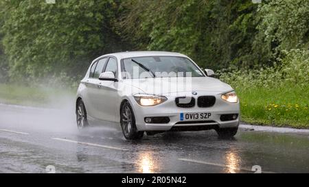 Stony Stratford, Bucks, Royaume-Uni - 6 mai 2023. 2013 BMW série 1 blanche conduite sous la pluie Banque D'Images