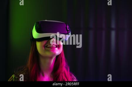 Jeune femme heureuse portant un casque de réalité virtuelle. La technologie immersive a apporté son immense plaisir, et elle semble pleinement engagée avec la digita Banque D'Images