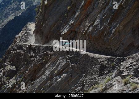 Une jeep robuste navigue sur une route dangereuse, sculptée entre des montagnes imposantes au Pakistan Banque D'Images