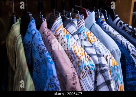 Variété colorée de tentures de chemises dans une salle d'exposition de vêtements. Mise au point rapprochée Banque D'Images