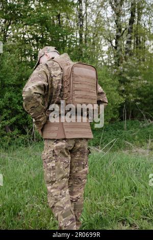 Vue arrière du soldat avec équipement complet et sac à dos tactique debout dans la forêt Banque D'Images