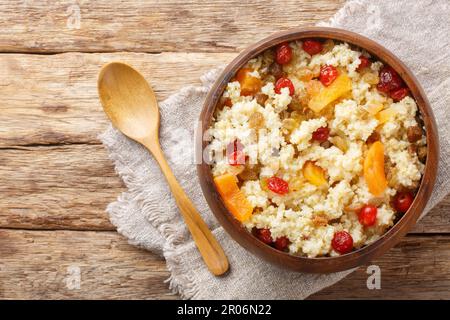 Porridge de millet doux avec des fruits secs tels que des raisins secs, des abricots, des cerises dans un bol sur la table. Vue horizontale du dessus Banque D'Images