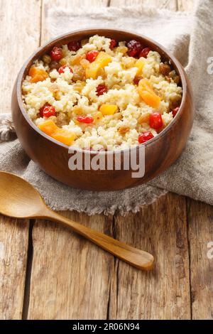 Porridge de millet doux aux raisins secs et aux abricots séchés, cerises en gros plan dans un bol sur la table. Verticale Banque D'Images