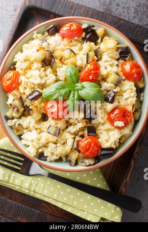 La nourriture végétarienne pour toute la famille a mis du porridge de millet avec des légumes et des herbes fraîches dans un bol sur la table. Vue verticale du dessus de l'ab Banque D'Images