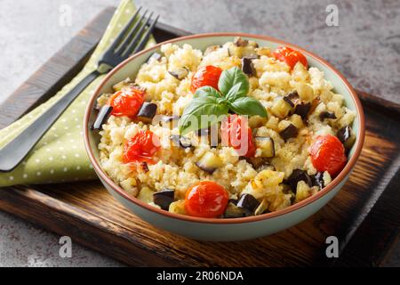 Millet savoureux avec tomate, aubergine, oignons gros plan dans un bol sur la table. Horizontale Banque D'Images