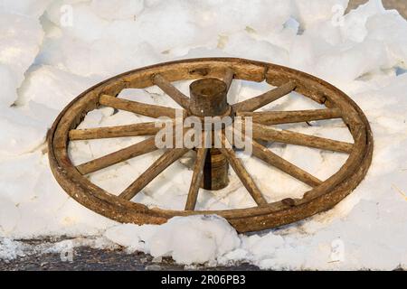 Ancienne roue de chariot. Détruire la roue en bois d'un chariot tiré par des chevaux est jeté sur la neige. Banque D'Images