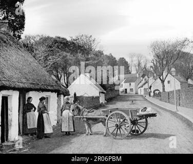 Vue de la fin du 19th siècle sur la vie de rue du village près de la côte Dublin/Wicklow, où une femme de poissons avec âne et chariot vend des produits aux habitants Banque D'Images