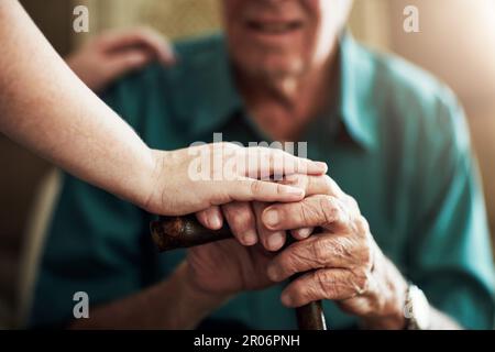 Il a tout le soutien dont il a besoin. une infirmière féminine méconnaissable qui aide son patient aîné à utiliser une canne en bois pour le soutenir. Banque D'Images