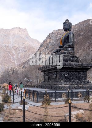 Une femelle routard à Muktinath, au Népal, priant dans la mudra de Namaste à l'énorme Bouddha de pierre. Banque D'Images