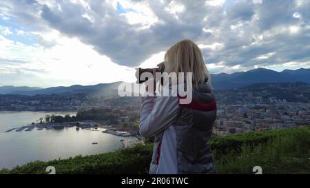 Jeune photographe prenant des photos au sommet de la ville de Lugano, près du lac de Lugano en Suisse. Belvédère avec vue aérienne depuis la colline de San Michele. Lugano Banque D'Images