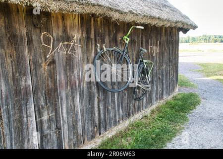 Un ancien vélo suspendu d'un hangar en bois Banque D'Images