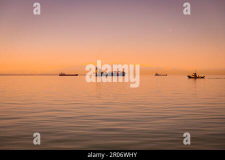 De grands navires cargo naviguant sur une vaste étendue d'eau libre au coucher du soleil à Thessalonique, Grèce Banque D'Images