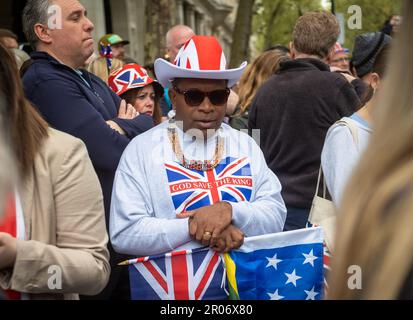 Dans une mer de gens célébrant le couronnement du roi Charles III à Londres, au Royaume-Uni, un homme noir d'âge moyen se distingue avec son chapeau Union Jack et ses gris Banque D'Images