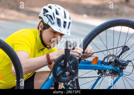 Un coureur mâle vérifie l'état du pignon pendant une courte pause. Inspection et entretien rapides de l'équipement. Banque D'Images