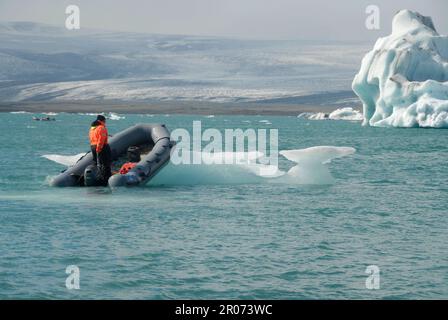 11 août 2022, Islande, Jökulsarlon : un petit bateau repousse un morceau de glace à Jökulsárlón, un lagon glaciaire dans le sud-est de l'Islande, pour faire place à des bateaux touristiques. Le lagon contient des icebergs de la langue du glacier Breiðamerkurjökull, qui fait partie du plus grand glacier Vatnajökull (le plus grand glacier d'Europe). Photo: Finn Huwald/dpa Banque D'Images