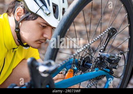 Un coureur mâle vérifie l'état du pignon pendant une courte pause. Inspection et entretien rapides de l'équipement. Gros plan. Banque D'Images