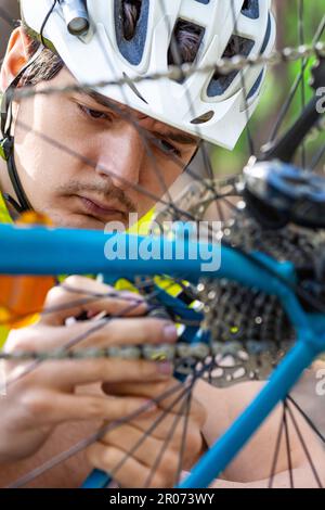 Photo verticale en gros plan d'un coureur qui vérifie l'état du pignon pendant une courte pause. L'inspection et l'entretien rapides de l'équipement sont la clé du succès Banque D'Images