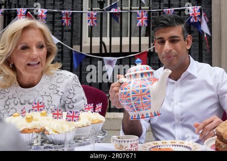 Le Premier ministre Rishi Sunak tient un grand pot à thé alors qu'il va verser une tasse alors qu'il est assis à côté de la première dame des États-Unis Jill Biden lors d'un grand déjeuner de couronnement à Downing Street, Londres, pour des volontaires, des réfugiés ukrainiens au Royaume-Uni, et des groupes de jeunes. Des milliers de personnes à travers le pays célèbrent le grand déjeuner de Coronation dimanche pour marquer le couronnement du roi Charles III et de la reine Camilla. Date de la photo: Dimanche 7 mai 2023. Banque D'Images