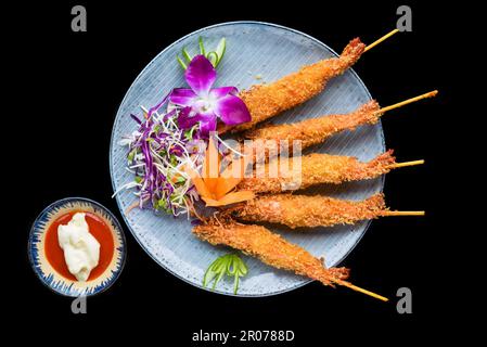 Crevettes frites en pâte avec sauce rouge isolée sur fond noir vue de dessus Banque D'Images