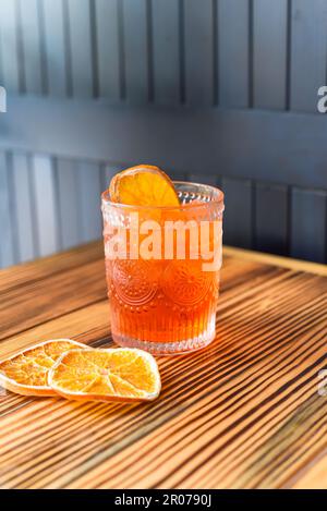 Cocktail d'alcool Aperol Spritz avec une sise d'orange sur une table en bois contre un mur sombre avec un espace de copie Banque D'Images