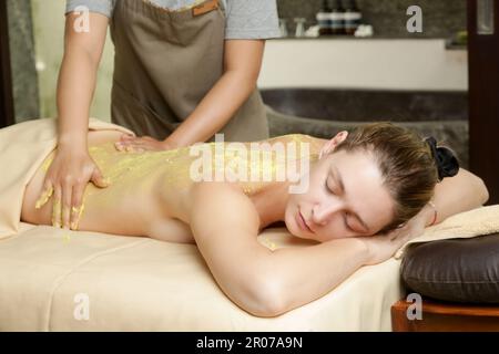 Jeune femme au spa de beauté naturelle ayant un soin gommage du corps. Relaxation, désintoxication, exfoliation de la peau rajeunissement concept. Banque D'Images