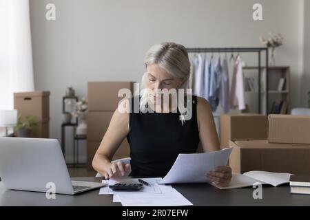Personne responsable de boutique Internet spécialisée femme calculant les dépenses, Banque D'Images