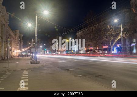 Chisinau, Moldavie - 8 mars 2023: Rue avec des sentiers de voiture légers dans le centre ville de Chisinau la nuit. Banque D'Images