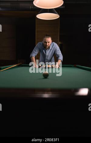 Homme caucasien élégant mettant des boules de billard dans le rack triangulaire sur la table préparer au jeu Banque D'Images