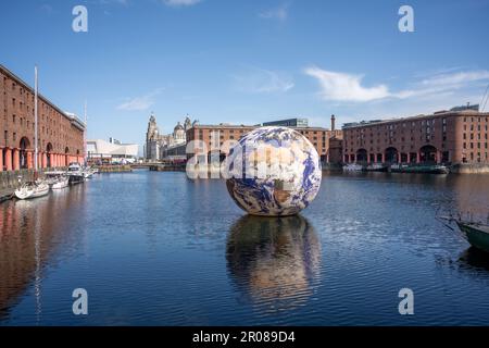 LIVERPOOL 7th MAI 2023: Une photographie documentant l'installation artistique de Luke Jerram, Floating Earth, à l'Albert Dock de Liverpool avec le Liver Buildi Banque D'Images