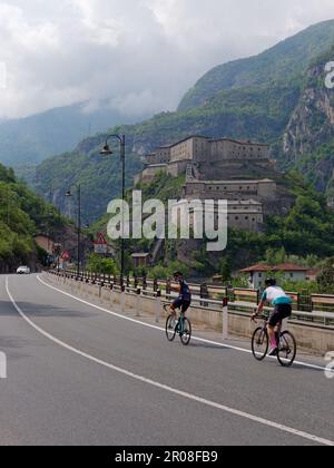 Les cyclistes passent par le fort de Bard (forte di Bard) dans la vallée d'Aoste, au nord-ouest de l'Italie Banque D'Images