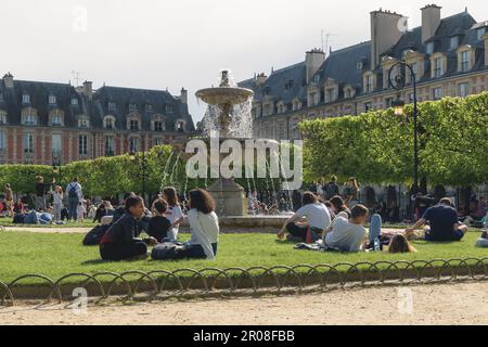 Tourisme et visiteurs assis dans le jardin de la place des Vosges à Paris. Banque D'Images