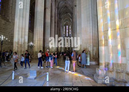 Batalha, Portugal - 15 août 2022: Intérieur du monastère gothique montrant l'autel avec croix, vitraux, ragoûts et de nombreux touristes Banque D'Images