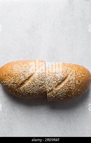 Pain artisanal recouvert de graines de sésame coupées en deux, vue de dessus du pain enrobé de sésame, pain sandwich coupé en deux Banque D'Images