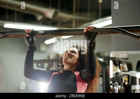 Posséder son entraînement. une jeune femme qui fait des exercices de pull-up à la salle de gym. Banque D'Images