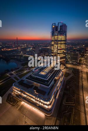 Budapest, Hongrie - vue panoramique verticale aérienne du campus de MOL, le nouveau gratte-ciel éclairé de Budapest à Kopaszi-gat par la rive au crépuscule Banque D'Images