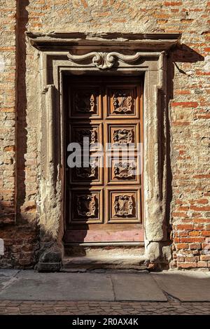 Ancienne porte en bois ornée d'époque et vieux mur en briques à Alba, Piémont, Italie du Nord (composition verticale). Banque D'Images