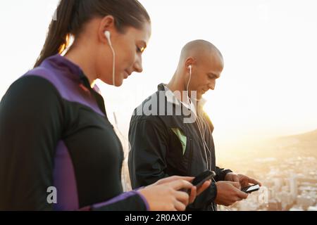 La liste de lecture idéale a été mise en ligne pour cette course. Un couple qui choisit de la musique sur son téléphone portable avant son entraînement à la course. Banque D'Images