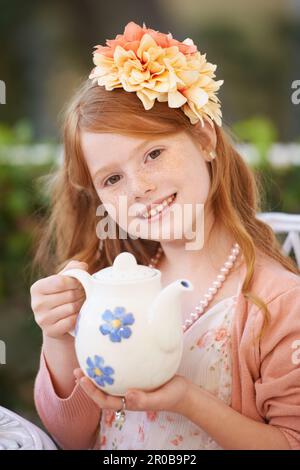 Voulez-vous du thé ? Adorable fille à tête rouge jouant robe et tenant une tasse de thé. Banque D'Images