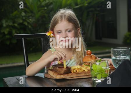 Petite fille mangeant des frites avec de la sauce tomate au restaurant Banque D'Images