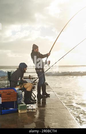 Faire un peu de pêche. deux jeunes hommes pêchant sur un quai. Banque D'Images