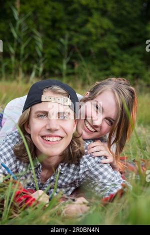 Portrait d'un jeune couple couché dans la prairie et souriant, Bavière, Allemagne Banque D'Images